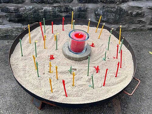 Eine Feuerschale mit Kerzen, jede Kerze steht für ein Verstorbenen